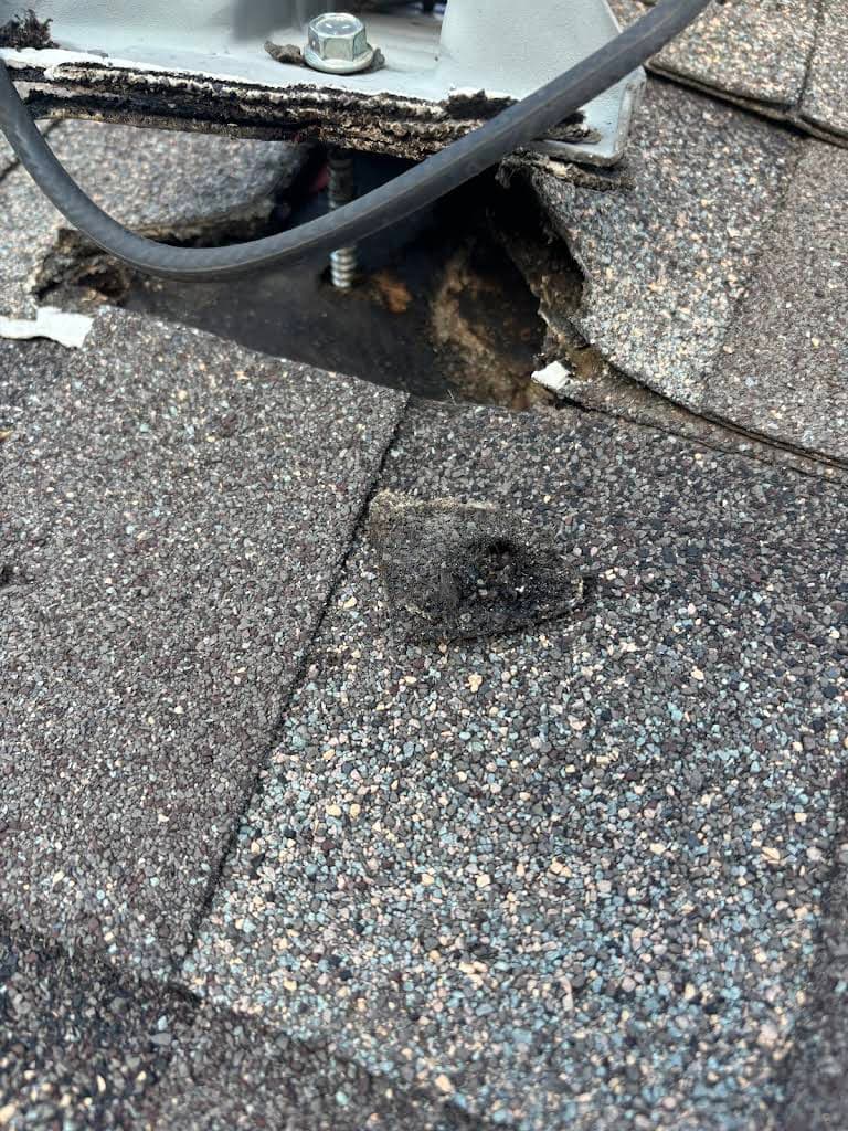 Before repair: a hole and deteriorated roof decking beneath Jacob Cobb’s satellite mount